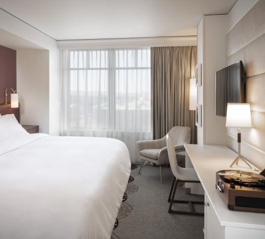 A standard King room at the Elizabeth Hotel in Fort Collins, featuring a large bed, wall-mounted TV and bright window