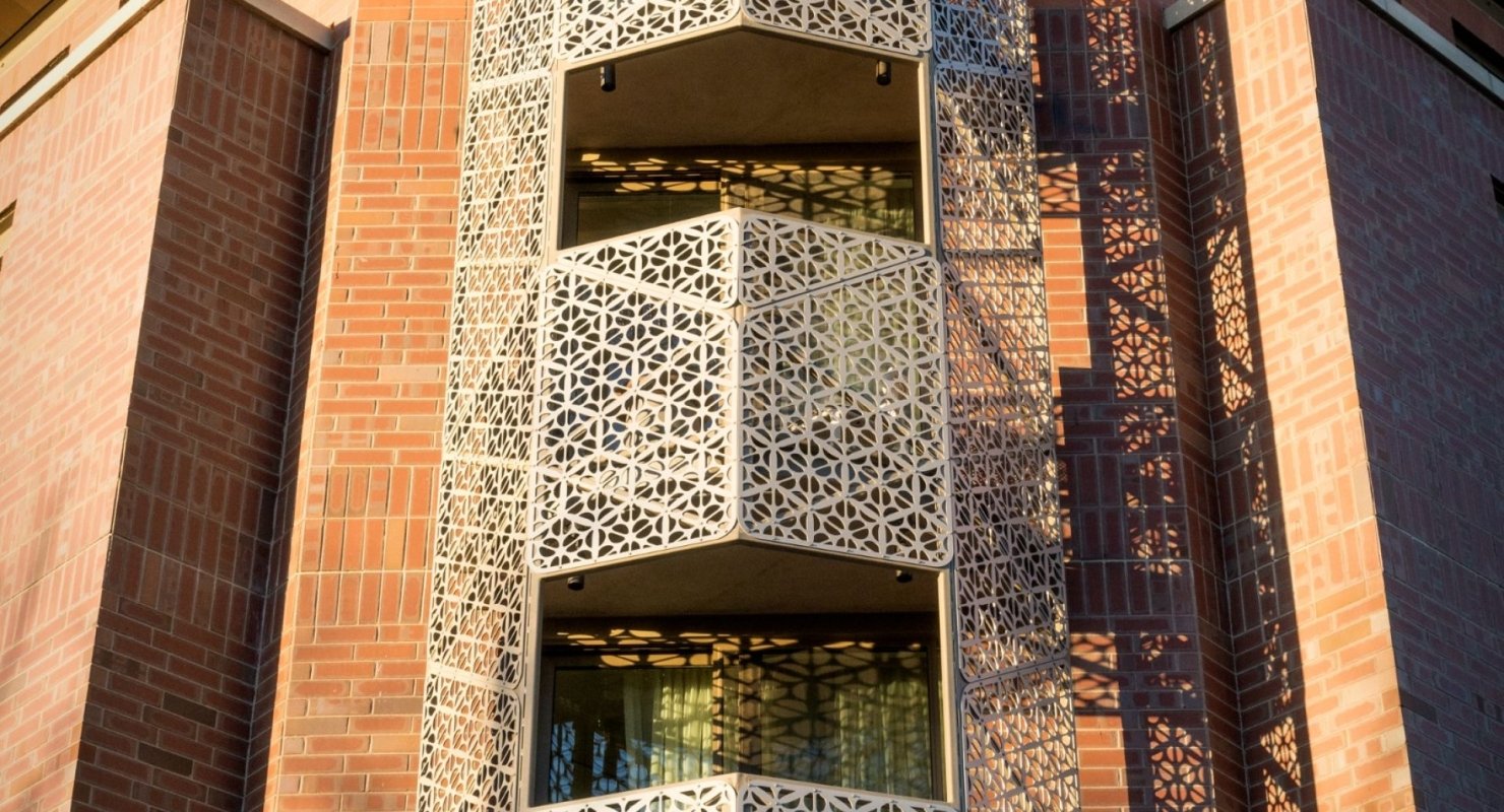 A close-up of a stylish, ornate balcony with a geometric, laser-cut metal screen.