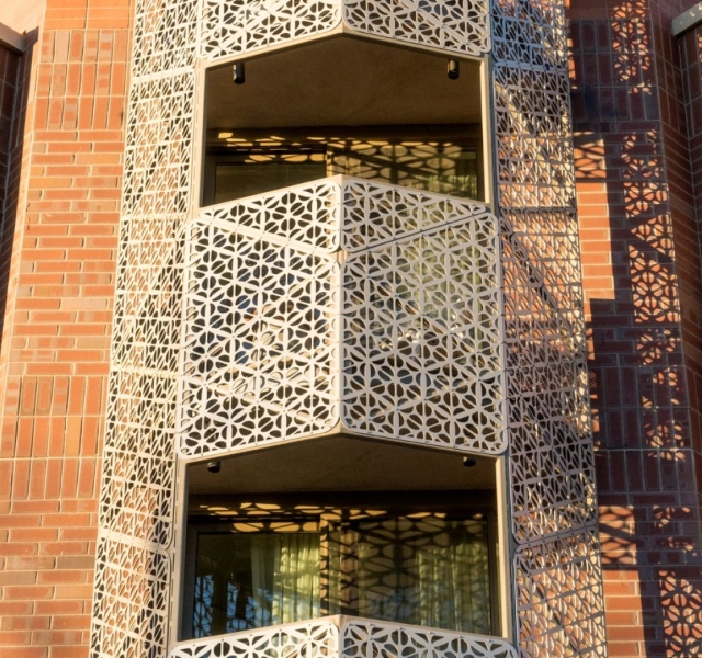 A close-up of a stylish, ornate balcony with a geometric, laser-cut metal screen.