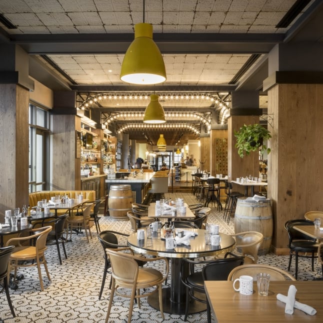 The elegant and spacious interior of a restaurant with high ceilings, sophisticated decor, and various seating arrangements.