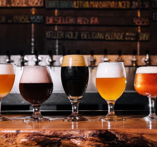 different types of craft beer in glasses on table in pub interior in daylight