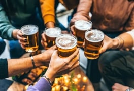 Group of friends drinking and toasting glass of beer at brewery pub restaurant- Happy multiracial people enjoying happy hour with pint sitting at bar table- Youth Food and beverage lifestyle concept
