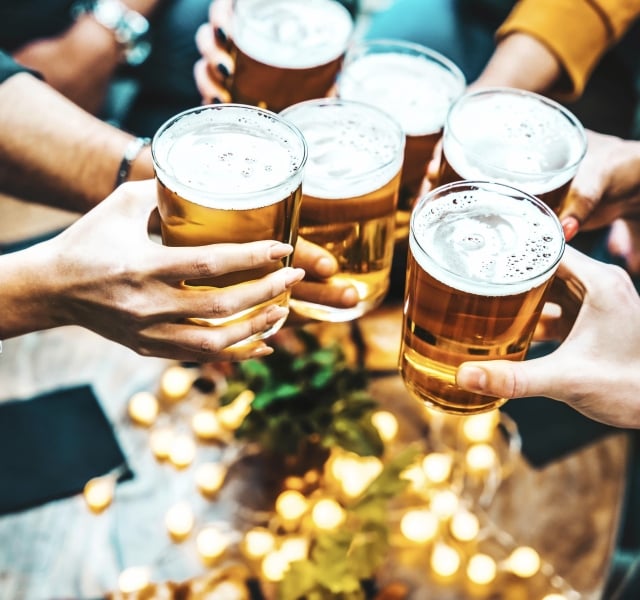 Group of people drinking beer at brewery pub restaurant - Happy friends enjoying happy hour sitting at bar table - Closeup image of brew glasses - Food and beverage lifestyle concept