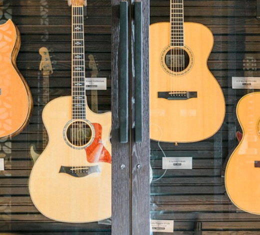 Three acoustic guitars hanging on a textured wall, likely in a music room or studio.