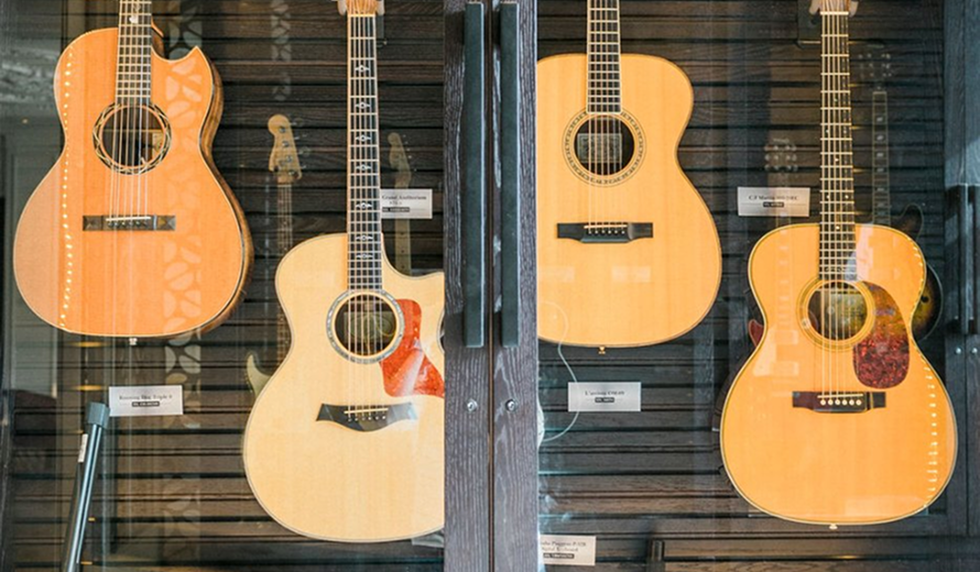 Three acoustic guitars hanging on a textured wall, likely in a music room or studio.