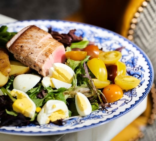 A Nicoise salad, with grilled tuna atop a bowl of greens, cherry tomatoes and hard boiled eggs
