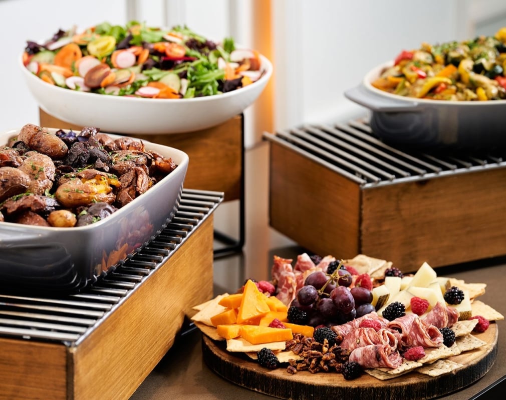 A buffet table with plates featuring meats and cheeses