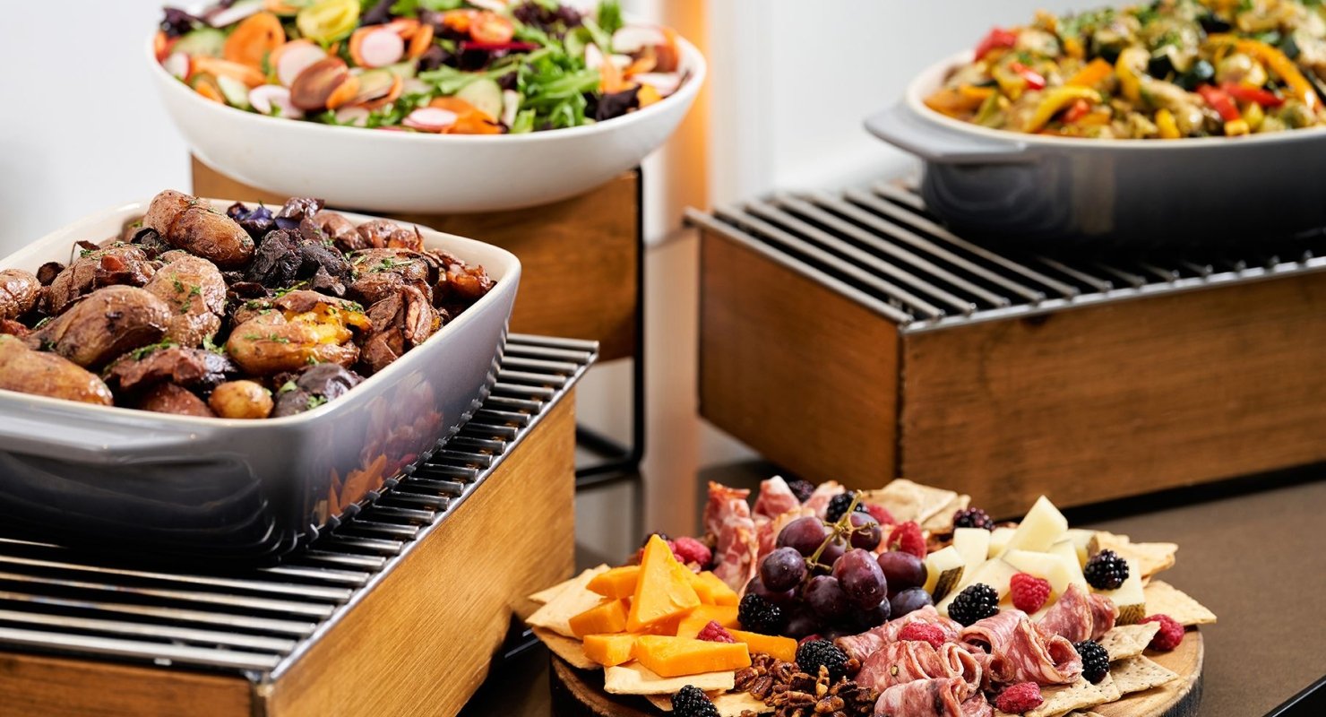 A buffet table with plates featuring meats and cheeses