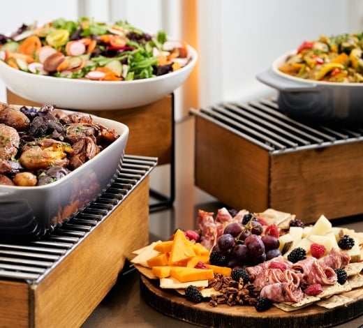 A buffet table with plates featuring meats and cheeses
