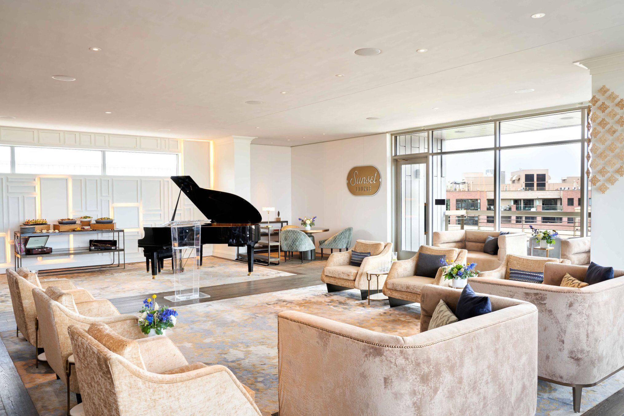A circle of comfortable lounge chairs set up around a grand piano at the Sunset Lounge
