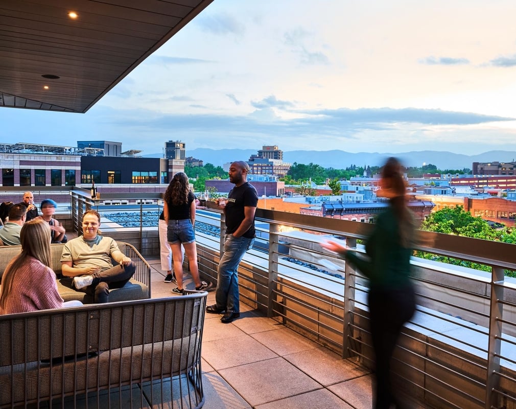 Patrons on the patio of the sunset lounge relax on outdoor seating, with Fort Collins in the background
