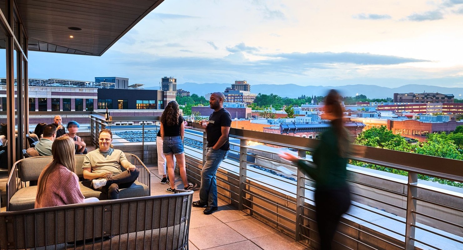 Patrons on the patio of the sunset lounge relax on outdoor seating, with Fort Collins in the background