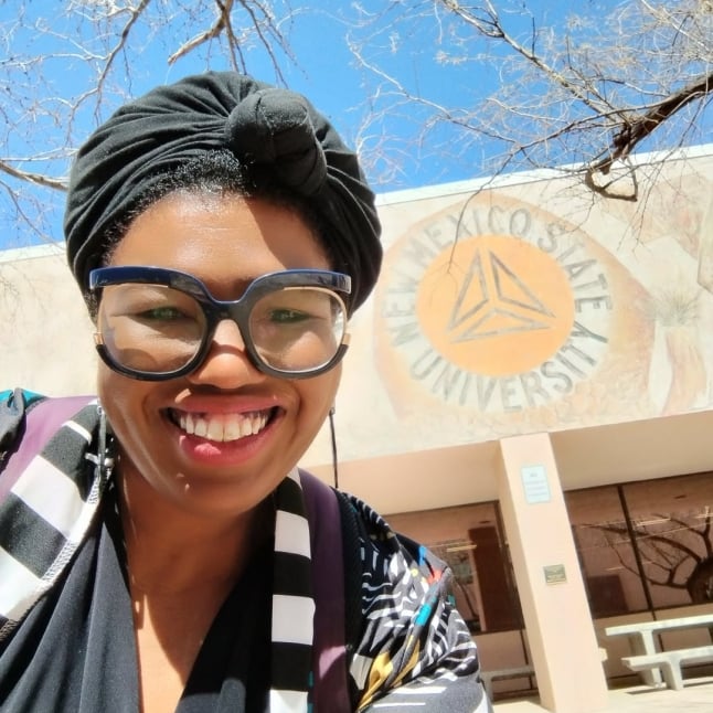 Kay Emerson posing in front of New Mexico State University