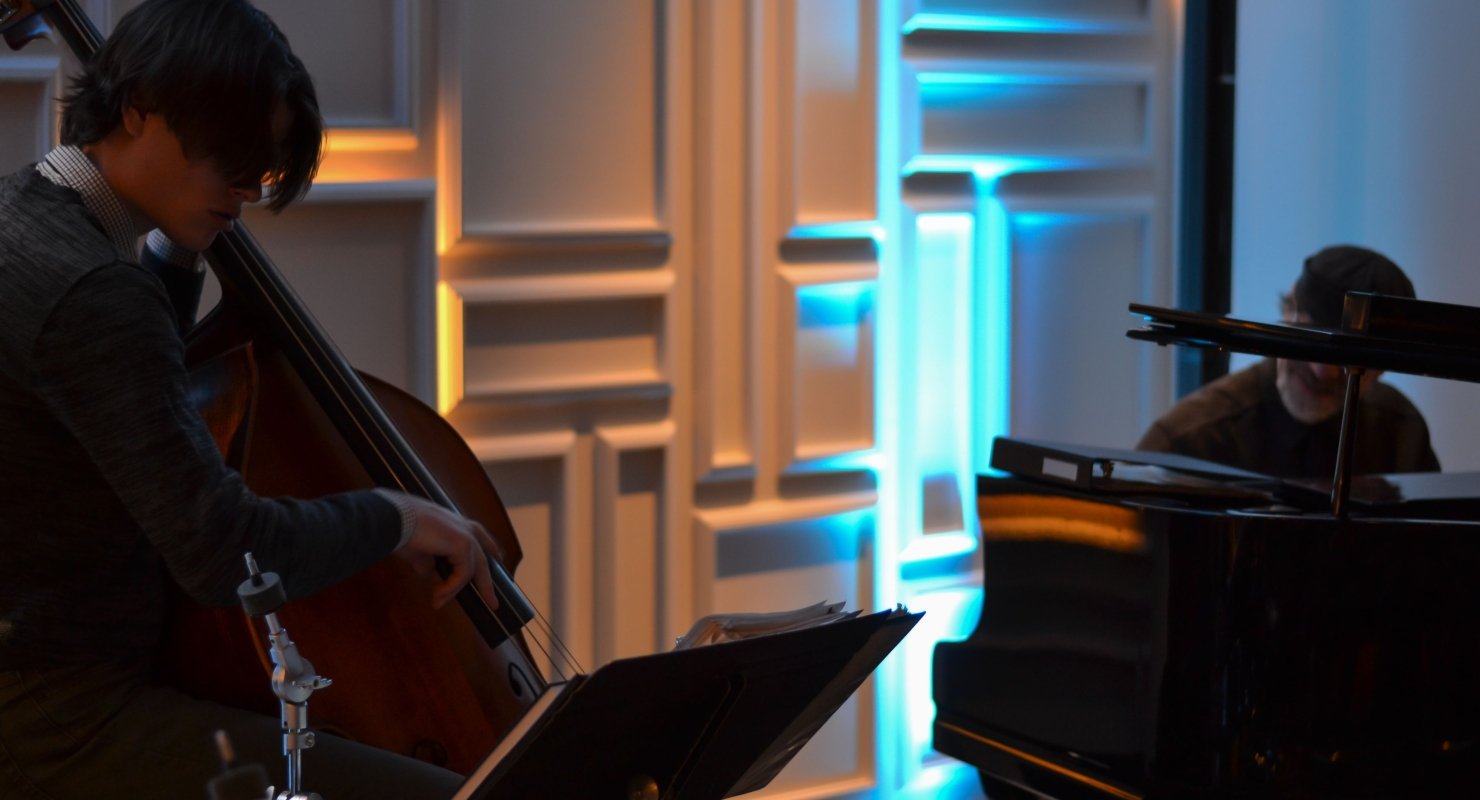 A standup bass player and a pianist perform in a dimly lit room