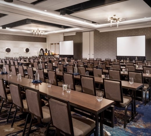 A boardroom at the Elizabeth, with rows of desks set up facing two large screens for a presentation