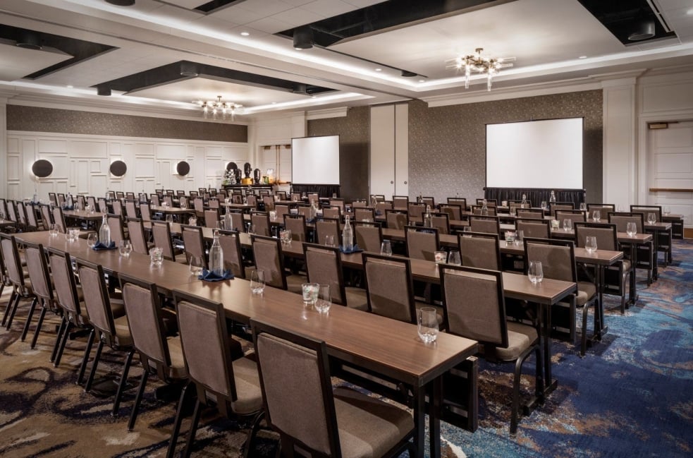 A boardroom at the Elizabeth, with rows of desks set up facing two large screens for a presentation