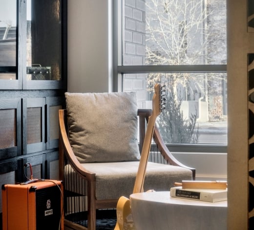 An electric guitar leaning against a coffee table with an orange amplifier nearby in a cozy room