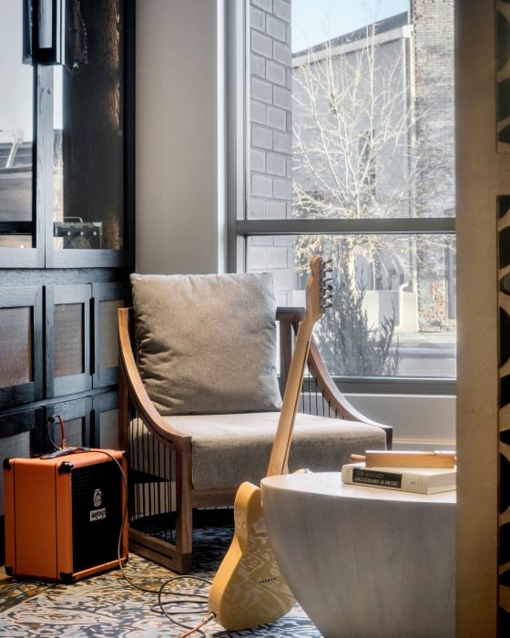 An electric guitar leaning against a coffee table with an orange amplifier nearby in a cozy room