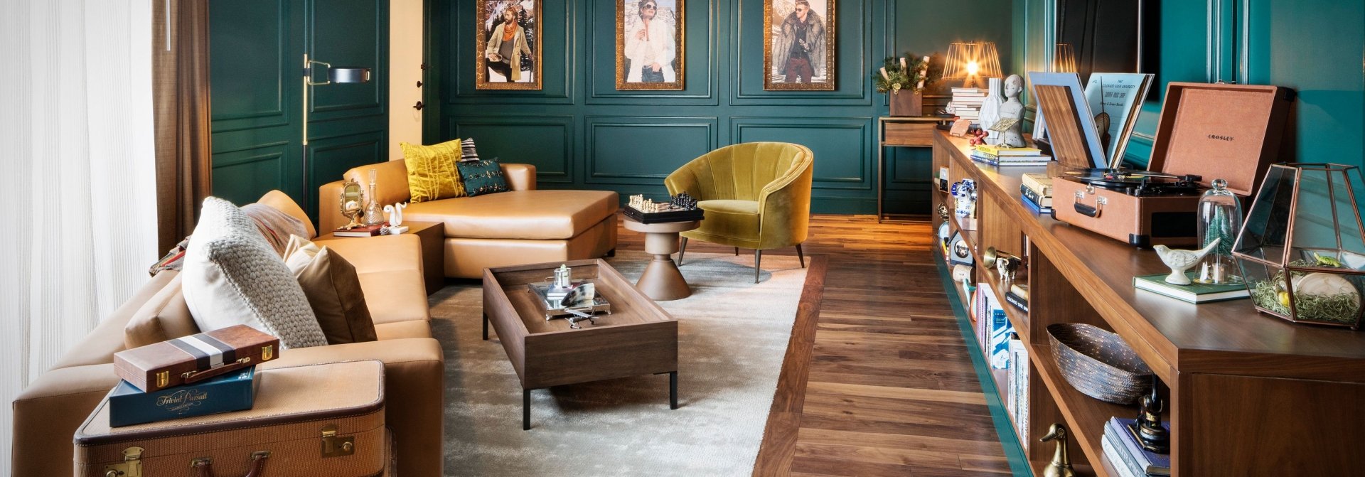 An elegant salon, with hardwood floors, ample seating and deep green-painted walls decorated with art