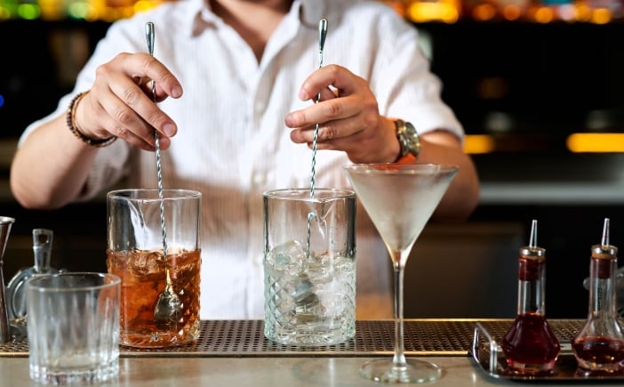 A bartender stirring two cocktails