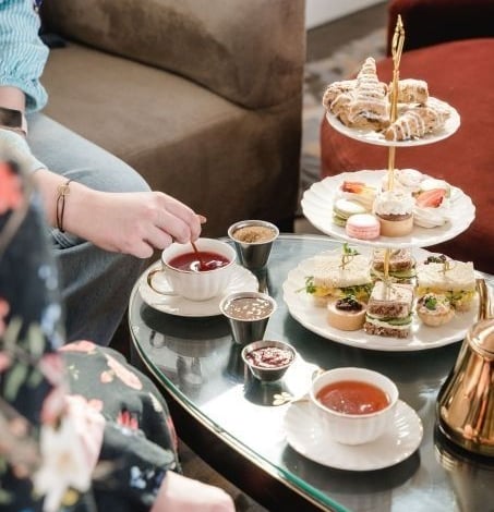 A table set up for high tea at the Sunset Lounge, with a cake tower featuring macarons and pastries and a tray of hot tea