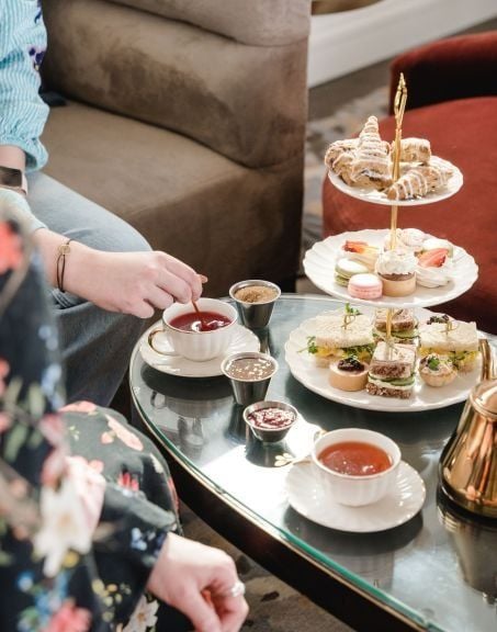 A table set up for high tea at the Sunset Lounge, with a cake tower featuring macarons and pastries and a tray of hot tea