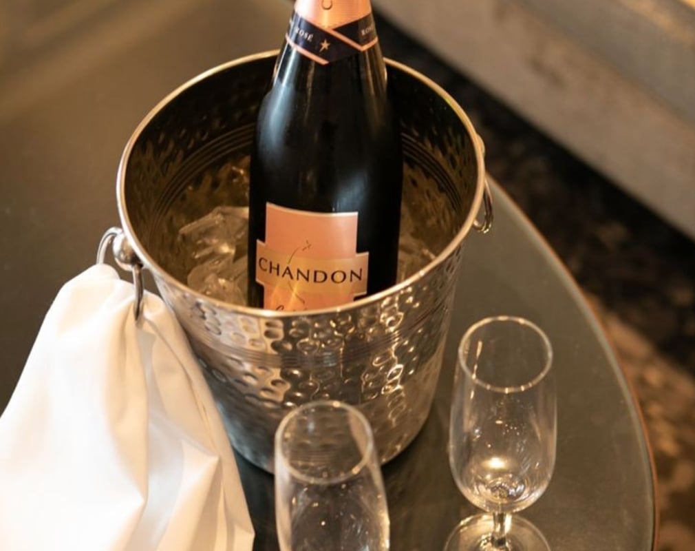 A bottle of Chandon on ice, with two champagne glassed on a silver tray