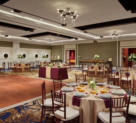 A ballroom set up for a wedding, with flower-topped banquet tables and a dance floor