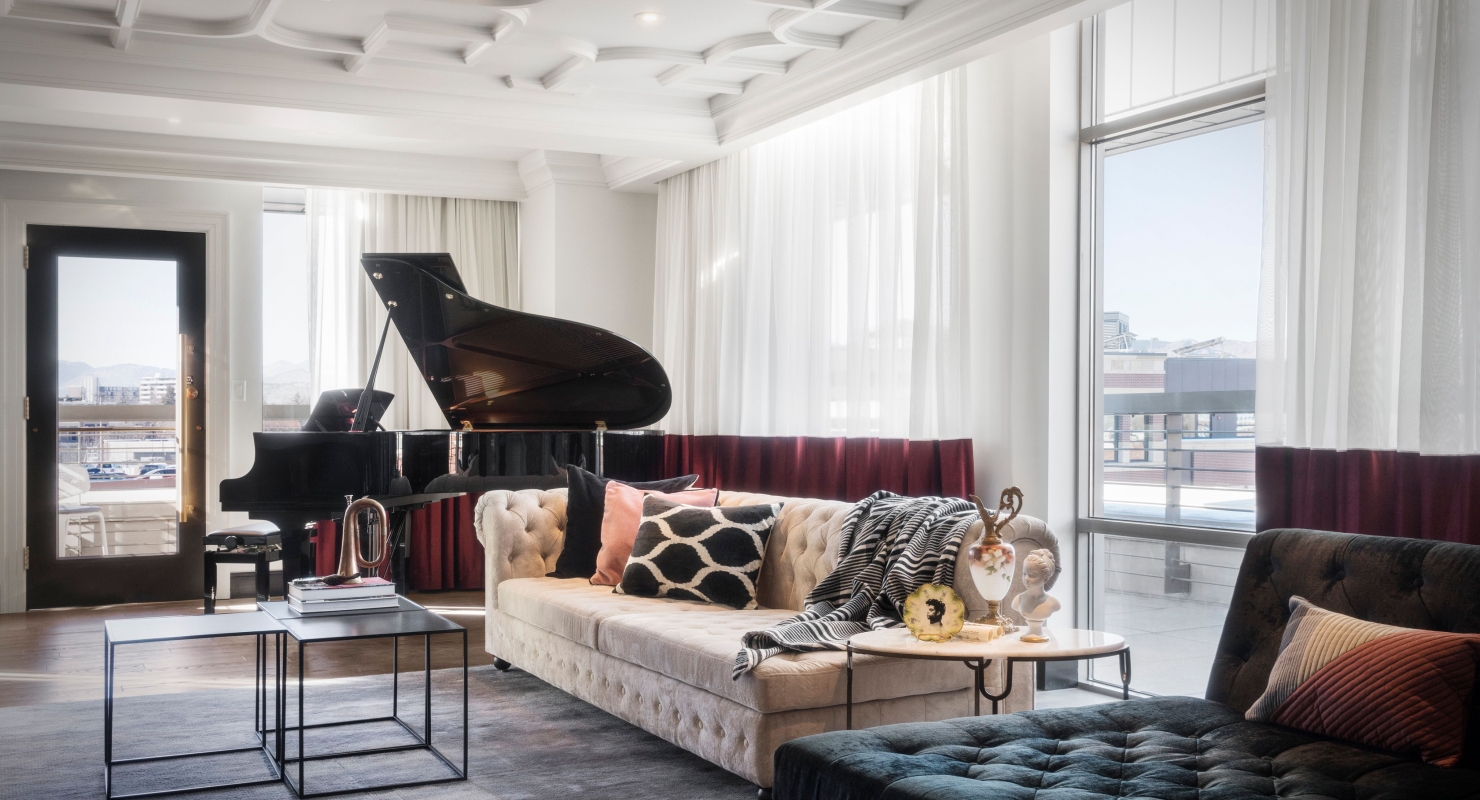 An Elizabeth Hotel suite, with a high ornate white ceiling, large couch and a grand piano