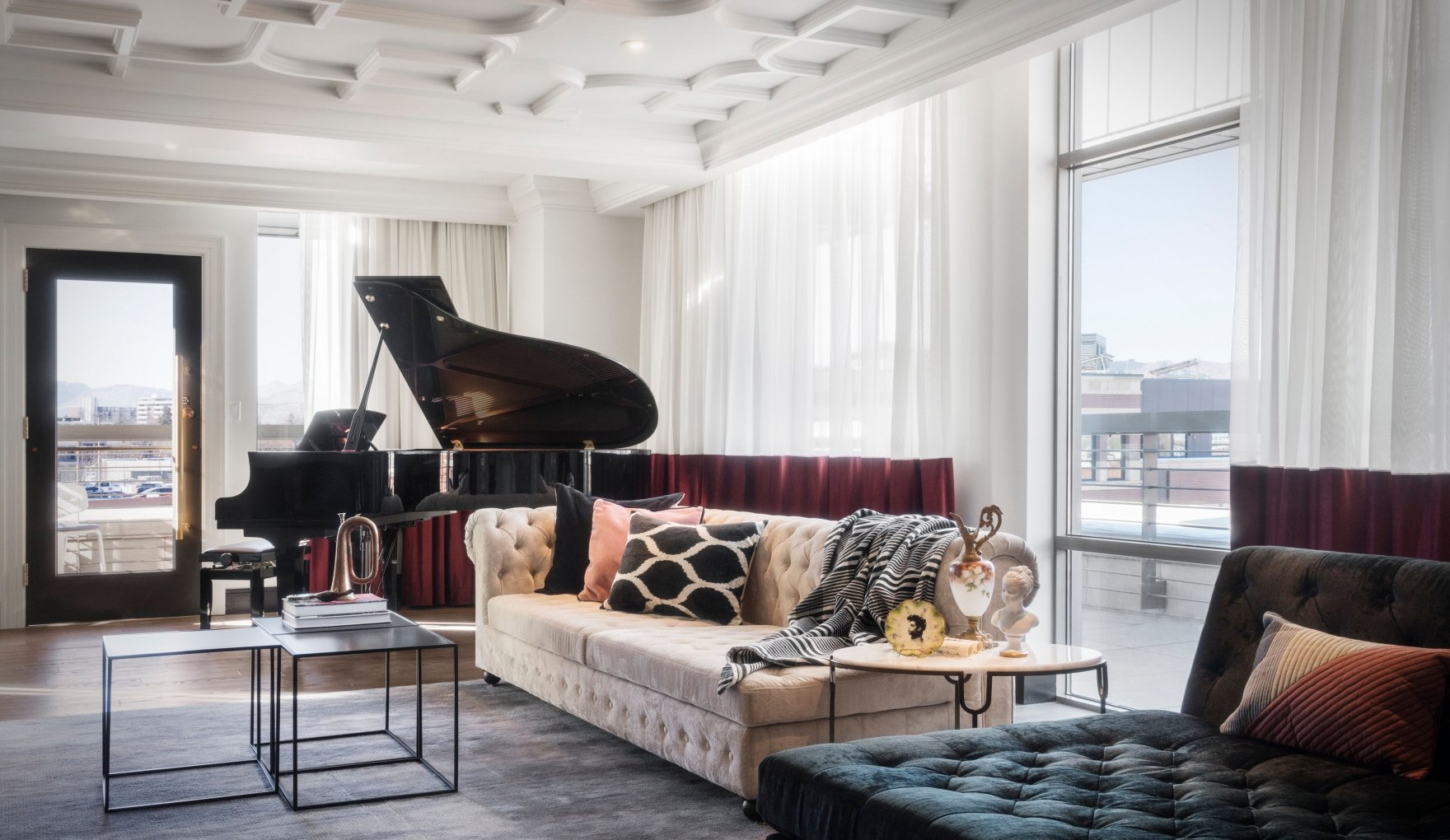 An Elizabeth Hotel suite, with a high ornate white ceiling, large couch and a grand piano