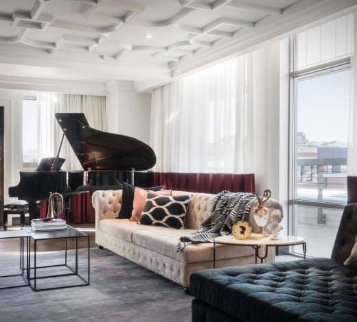 An Elizabeth Hotel suite, with a high ornate white ceiling, large couch and a grand piano