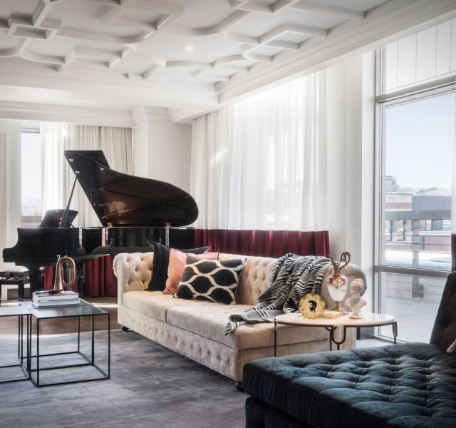 An Elizabeth Hotel suite, with a high ornate white ceiling, large couch and a grand piano
