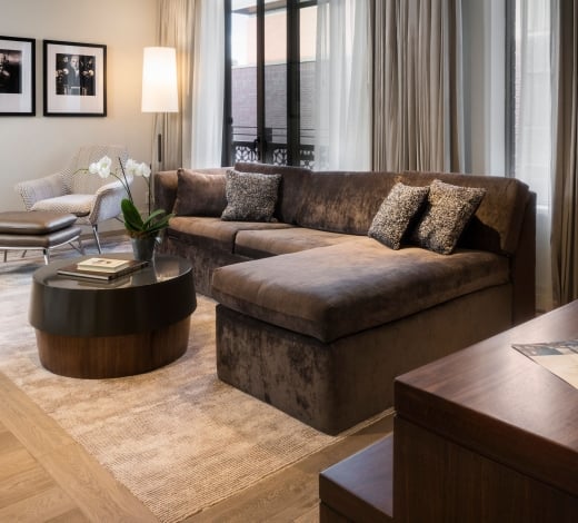 An Elizabeth Hotel suite living room with a large sectional couch, coffee table and workspace