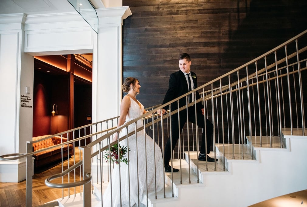 A bride and groom ascending a staircase in the lobby of the Elizabeth Hotel