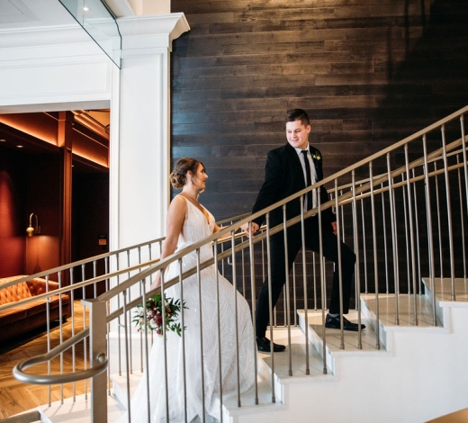 A bride and groom ascending a staircase in the lobby of the Elizabeth Hotel