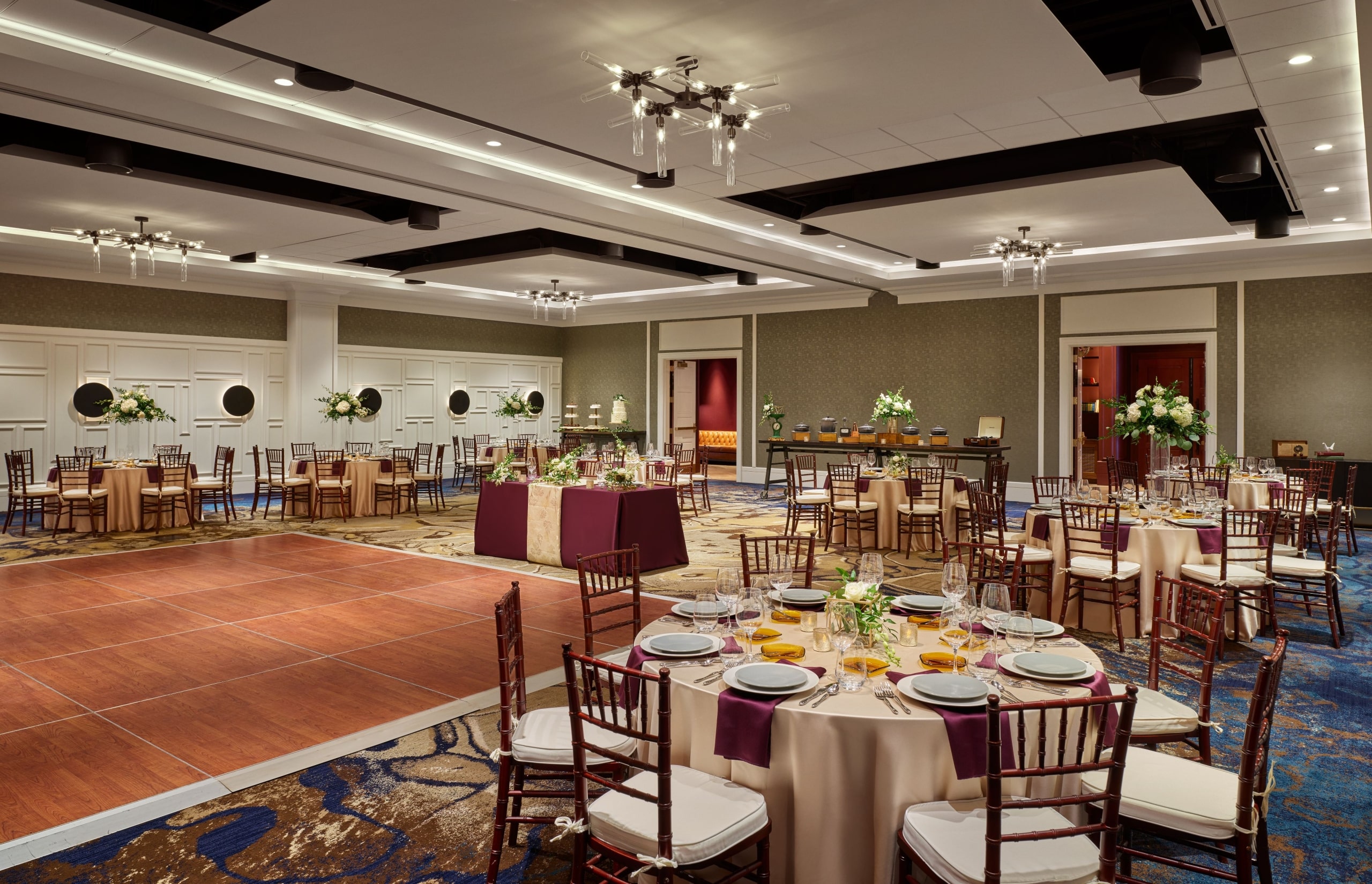 A ballroom set up for a wedding, with flower-topped banquet tables and a dance floor