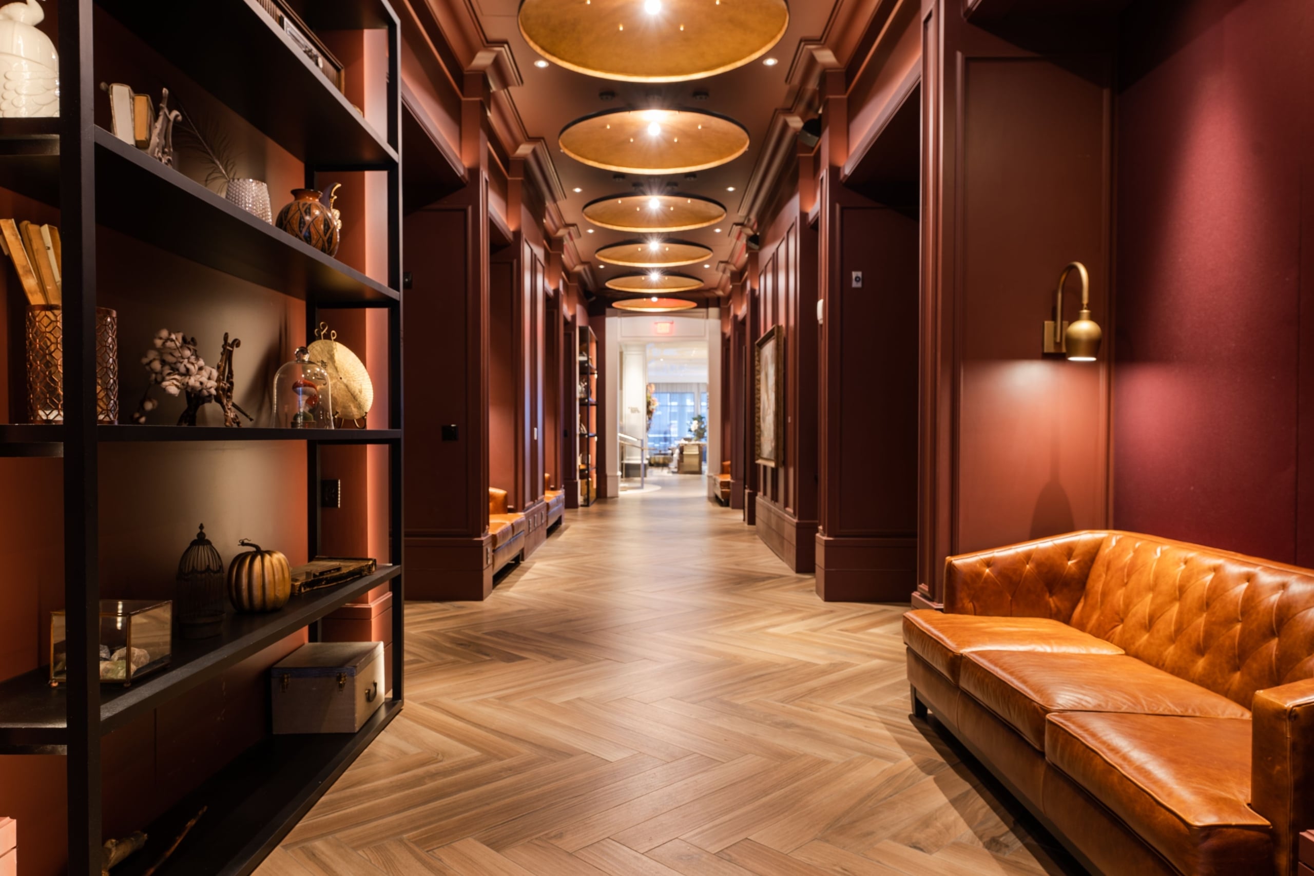 A long hallway red walls and parquet flooring in the lobby of The Elizabeth Hotel