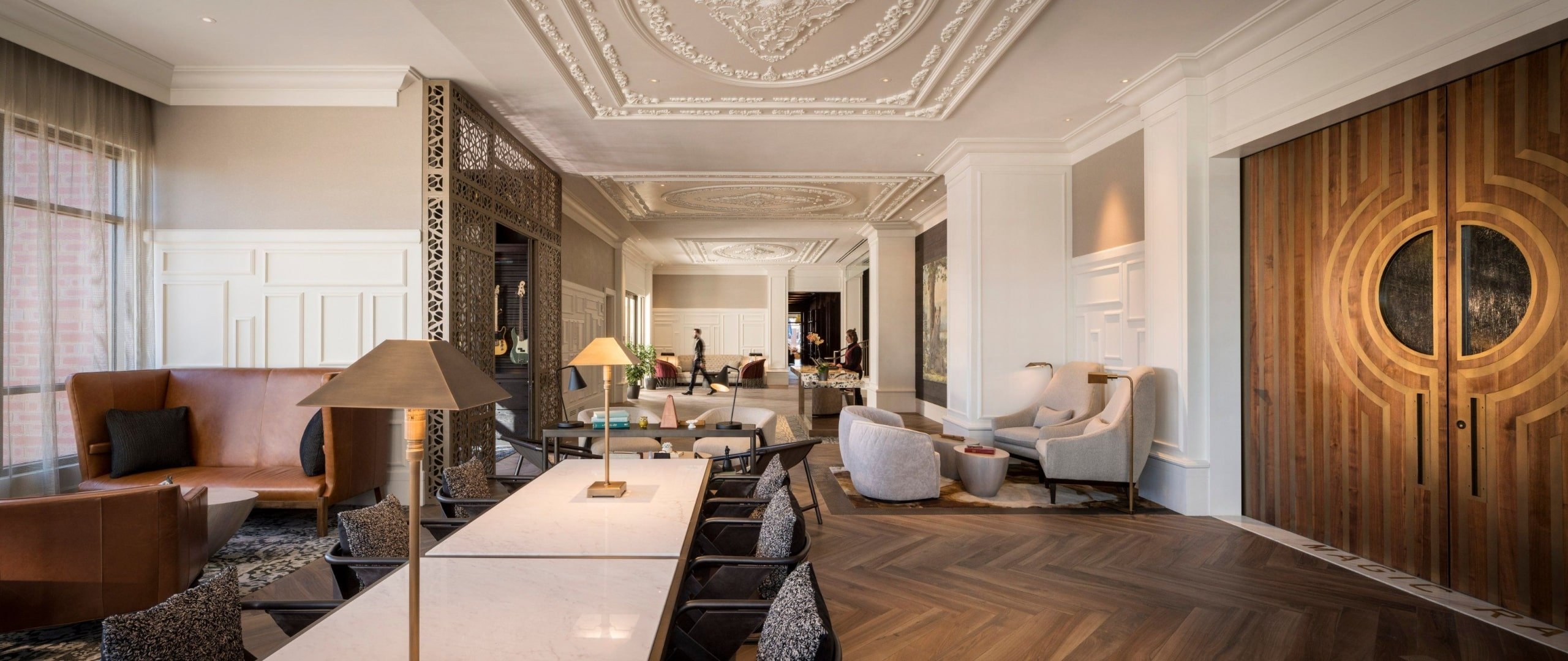 The lobby of the Elizabeth, a seating area with plush chaises and high white ceilings with ornate molding
