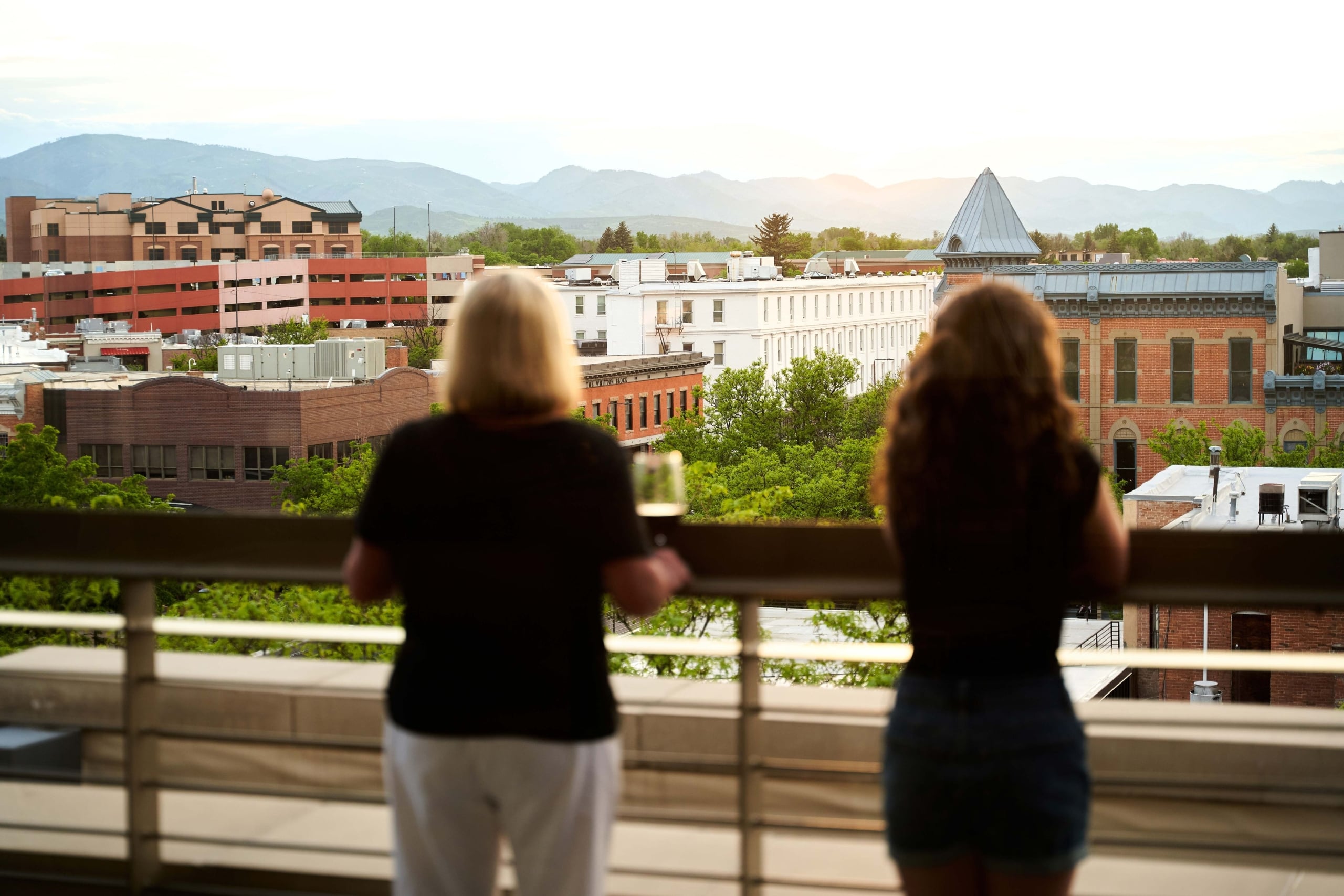 Two people look out on the horizon of Fort Collins from a balcony at the Elizabeth Hotel