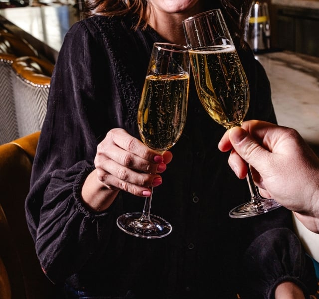 Two people clinking glasses of bubbly